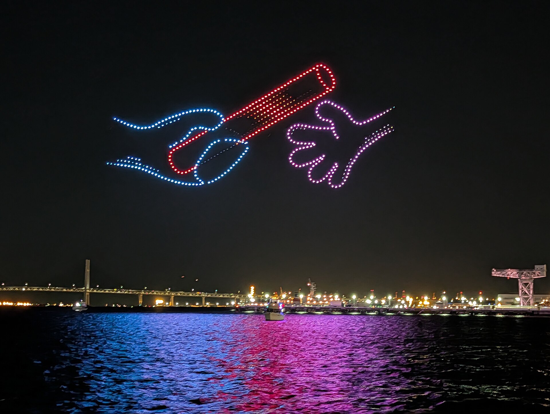 Drone light show forming a glowing image over a harbor at night