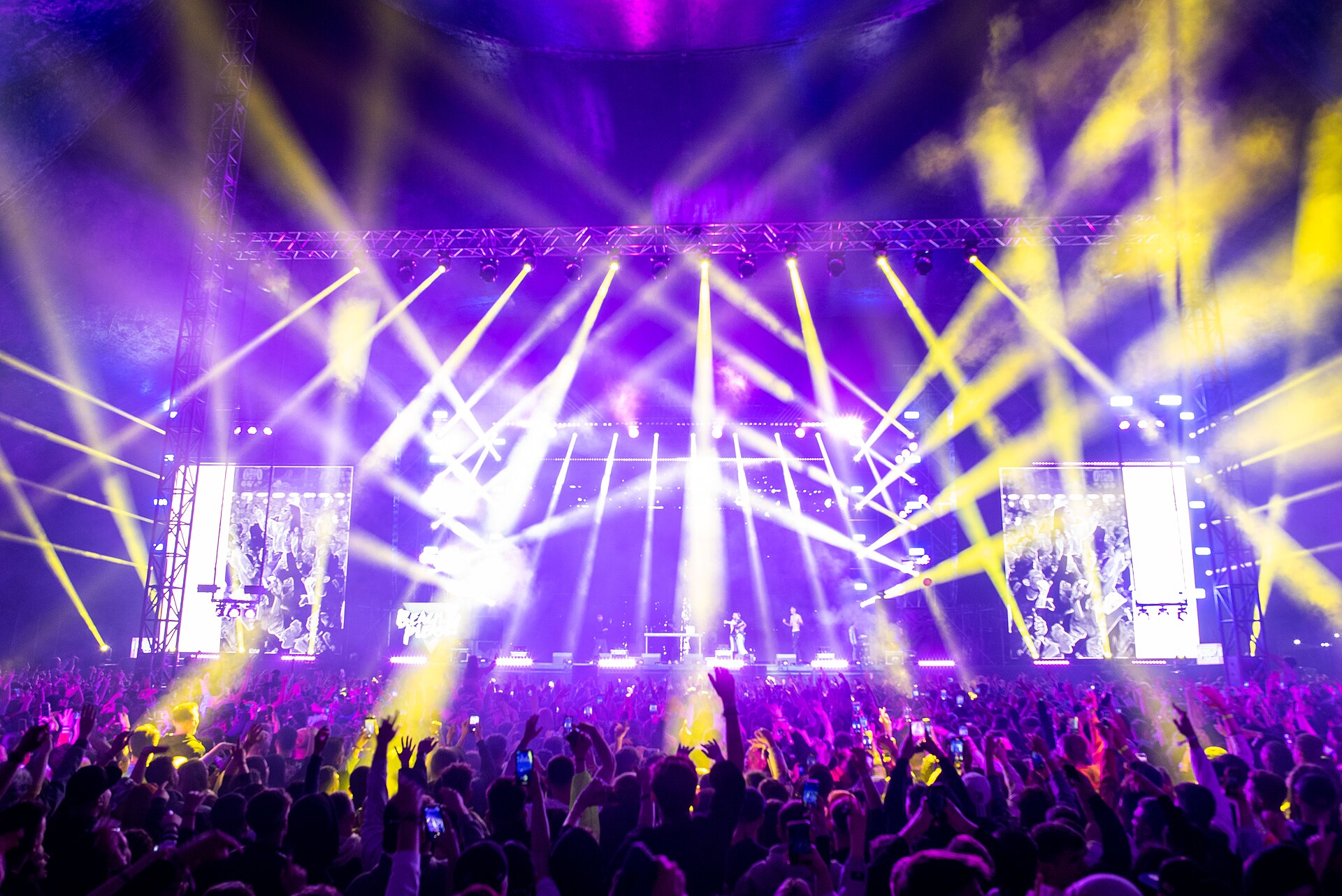 Large festival main stage with dramatic lighting beams over a big crowd